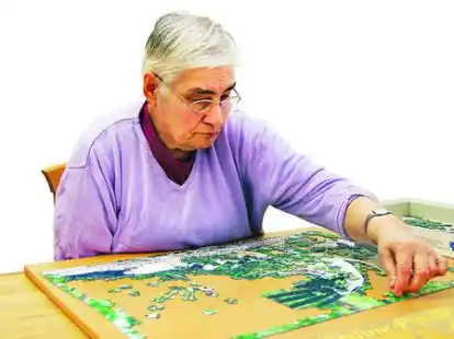 Konzentriert arbeitet die Rentnerin Hannelore an ihrem Puzzle. Es hat 1000 Teile und zeigt den Besuch der Altengruppe in der Storchenstation Berne. Rundes Bild: Ein anderer Rentner malt ein Zeichenheft aus