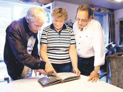 Jens Uwe B&ouml;ttcher, Aenne Fr&ouml;llje und Ralf-Roger schauen in ein altes Fotoalbum.