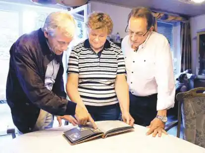 Jens Uwe B&ouml;ttcher, Aenne Fr&ouml;llje und Ralf-Roger schauen in ein altes Fotoalbum.