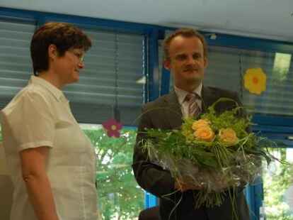 Schulleiter Jan P&ouml;ssel bedankt sich bei Sekret&auml;rin D&ouml;rthe Biedermann mit Blumen.