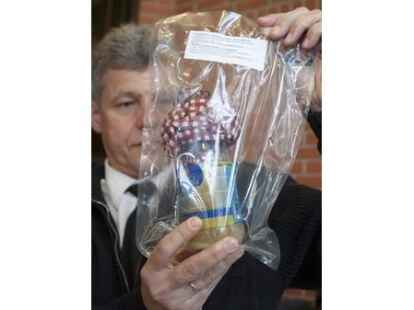 Ein Polizist h&auml;lt einen sichergestellten Molotowcocktail in die Kamera der Fotografen.