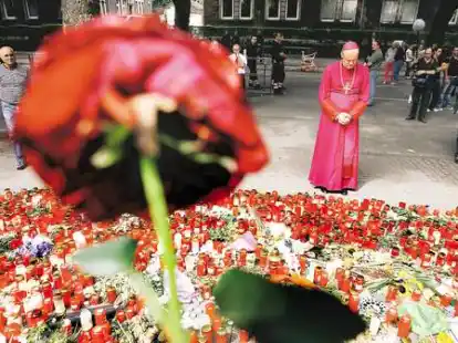 Stille Anteilnahme: Der Essener Bischof Franz-Josef Overbeck vor den Kerzen und Blumen f&uuml;r die Toten von Duisburg