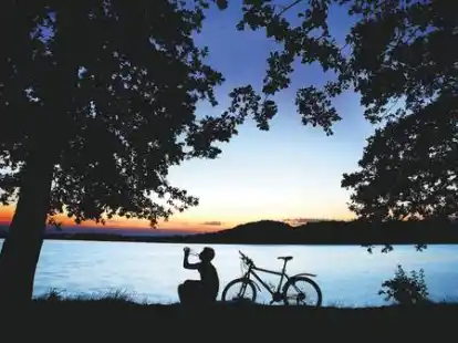 Pause zum Sonnenuntergang am Ufer des M&ouml;hnesees: Fahrradtouristen haben Zeit und Geld.