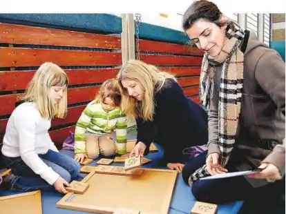 Die Sch&uuml;lerinnen Veronika (Klasse 3a) und Anastasia (1a) knobeln mit den Lehrerinnen Friederike von Alten-Rocholz und Nicole Hillar (von links) an einem magischen Quadrat.