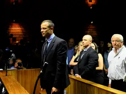 Sprintstar Oscar Pistorius bei seiner Anh&ouml;rung vor dem Magistratsgericht in Pretoria, hinter ihm sein Bruder  Carl  und sein  Vater Henke Pistorius.