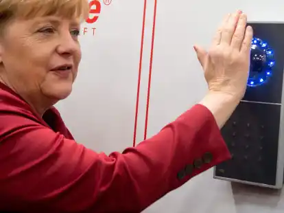 Bundeskanzlerin Angela Merkel versucht am Stand von Tisoware  mittels Scannen ihrer Hand Zutritt durch eine T&uuml;r zu erlangen.