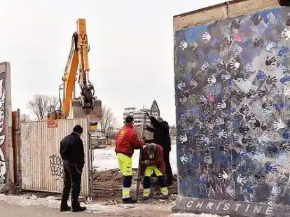 Und noch ein Loch: Polizisten standen am Mittwoch in Berlin vor der East Side Gallery hinter der der Arm eines Baggers zu sehen ist.