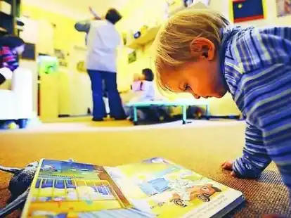 Pflegekind Milan (2) studiert im Bremer &bdquo;Kinderclub&ldquo; ein Bilderbuch.