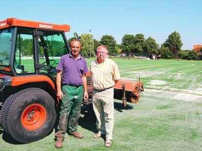 120 Tonnen Quarzsand verteilte Kay Werner (links) auf dem 8000-Quadratmeter-Platz mit einem Spezialfahrzeug. Rechts TuS-Vorsitzender Harald L&uuml;ers.