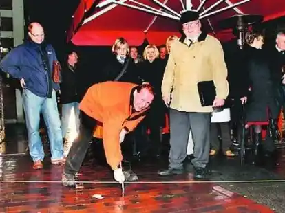 Heinrich Weymann misst die m&ouml;gliche Anhebung des Stra&szlig;enniveaus nach; rechts daneben Hartmut Frerichs.