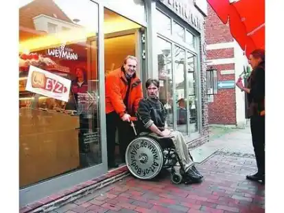 Stolperfalle beim Eingang in die B&auml;ckerei: Heinrich Weymann hilft einem Kunden mit Rollstuhl, Sven Reinke, in die B&auml;ckerei.