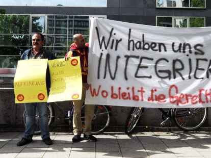 Eine Gruppe Demonstranten h&auml;lt verschiedene Transparente hoch.