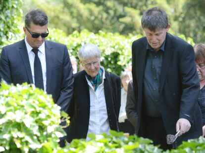 Inge Jens sowie ihre S&ouml;hne Christoph (links) und Tilmann trauern am Grab von Walter Jens.