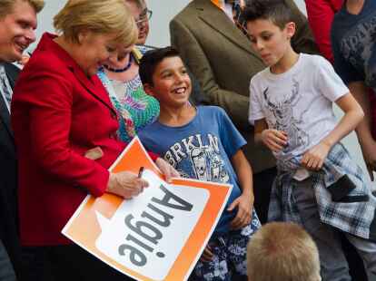 Bundeskanzlerin Angela Merkel (CDU) unterschreibt  ein Plakat während eines Wahlkampfauftritts in Ulm (Baden-Württemberg).