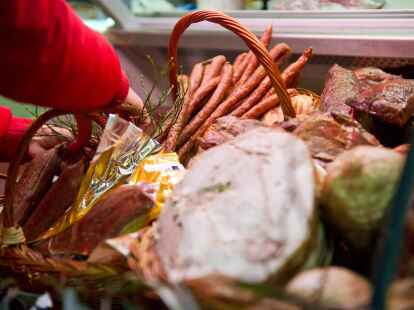 Eine Frau dekoriert   auf der Gr&uuml;nen Woche in Berlin eine Wursttheke.