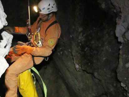 Ein Retter seilt sich in die H&ouml;hle ab.