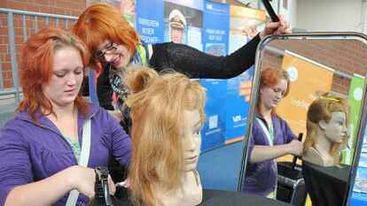 &bdquo;Lotti&ldquo; hei&szlig;t die Frisierpuppe, die Bianca Niehaus (hinten) mit an den Stand der Arto Team GmbH gebracht hatte. Wer wollte, konnte sich im Frisieren &uuml;ben.