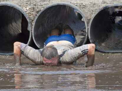 Ein Mann k&auml;mpft sich kopf&uuml;ber durch den Schlamm.