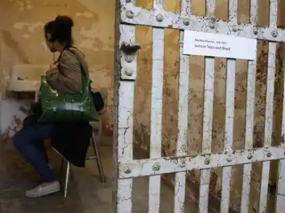 Eine Besucherin lauscht in einer Zelle einer Kunstbeschreibung.