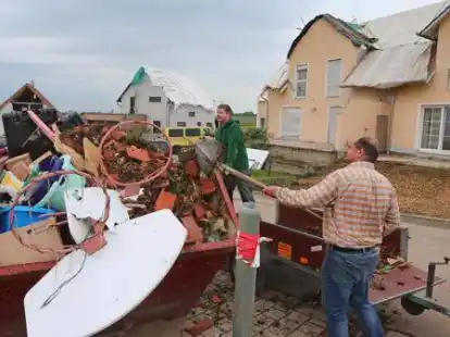 Helfer schaufeln in der Gemeinde Affing im Landkreis Aichach Friedberg vor einem besch&auml;digten Wohnhaus Dachziegel in einen mit Abfall gef&uuml;llten Container. Am zweiten Tag nach dem schweren Unwetter laufen in der betroffenen Region die Aufr&auml;umarbeiten auf Hochtouren.