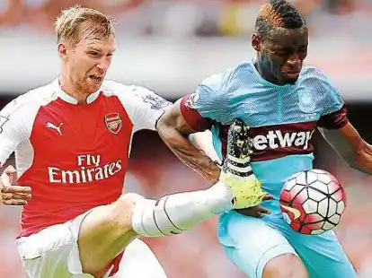 Verlor den Kampf um den Ball und das Spiel: Per Mertesacker (links)  und sein Club FC Arsenal unterlagen zum Liga-Auftakt  Diafra Sakho und West Ham United.