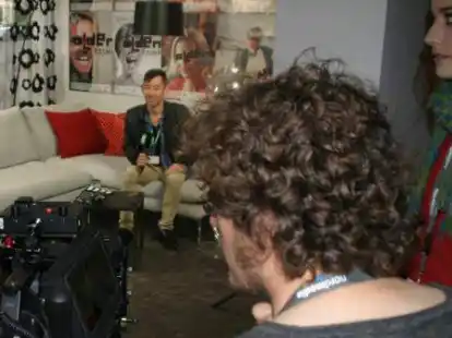 Auf geht&rsquo;s: Regisseur Kenny Riches ist auf dem Sofa &ndash; allein mit   Mikrofon   und Kaugummiautomat. Amon Thein (unten rechts) beobachtet die Szene auf dem Monitor der Kamera, Laura Groeneveld assistiert.