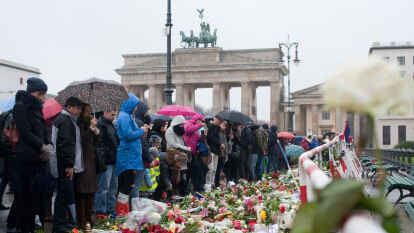 Trauernde stehen am Sonntag in der N&auml;he der franz&ouml;sischen Botschaft   in Berlin  auf dem Pariser Platz vor Blumen und Kerzen, die zum Gedenken an die Opfer der Terroranschl&auml;ge von Paris dort niedergelegt worden waren.