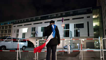 Zeichen der Solidarit&auml;t in Berlin: Ein Mann h&auml;lt vor der Franz&ouml;sischen Botschaft  die Flagge Frankreichs &uuml;ber auf seiner Schulter.
