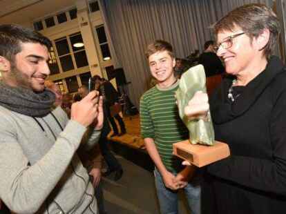 Nabil Almaami (l.) und Fiepko K&uuml;hn (m.) haben den Integrationspreis 2015 in der Endfassung gestaltet - Petra L&uuml;bbering vom ausgezeichneten Projekt &bdquo;Fahrr&auml;der f&uuml;r Fl&uuml;chtlinge am Fliegerhorst&ldquo; h&auml;lt ihn f&uuml;r ein Erinnerungsfoto hoch.