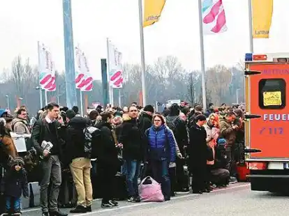 Flugg&auml;ste warteten vor den Terminals  zwischen Fahrzeugen der Feuerwehr auf Anweisungen.