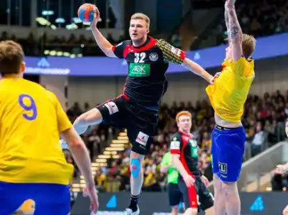 Philipp Weber (Mitte) aus Deutschland steigt vor der schwedischen Abwehr zum Wurf in die Luft.