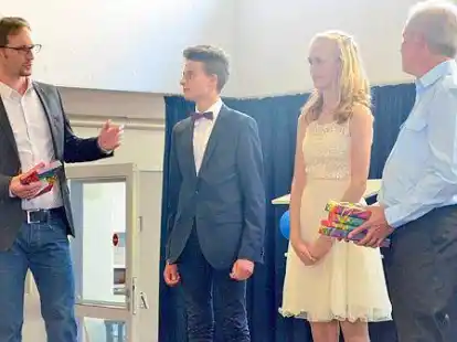 Abschlussfeier der zehnten Klassen: Schulleiter Arne Warnken (links) und sein Stellvertreter Thomas Reinsch &uuml;berreichen den Schulbesten Lena Kettler und Nick Feldmann ein Buch als besondere Anerkennung.