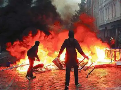 Randalierer stehen  im Schanzenviertel in Hamburg vor einer brennenden Barrikade. Die schweren Ausschreitungen rund um den G20-Gipfel in Hamburg besch&auml;ftigen B&uuml;rger und Politik seit Tagen.