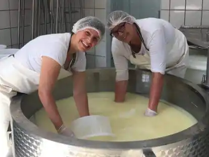 Anne Lang (links) und Marlies Brinkmann holen den K&auml;se-Bruch mit Sieben aus dem Kessel.