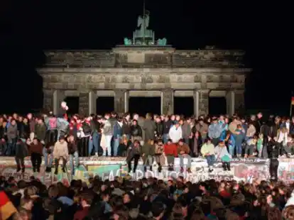 Jubelnde Menschen auf der Berliner Mauer am Brandenburger Tor am 10. November 1989. Was am 9. November 1989 geschah, war der Vorbote der deutschen Einheit.