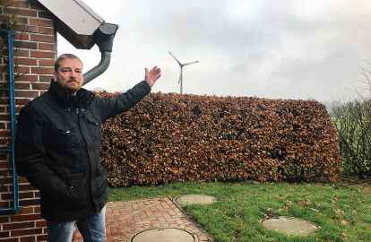 Sven Reschke-Luiken zeigt auf die Windkraft-Anlage hinter seinem Haus in Arle. (Foto: Lars Laue)