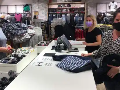 Kerstin Johannsen und Sandra Pollmann (von rechts) von Jeans Fritz in Aurich bedienen Kundin Monika Behrends mit Mundschutz.