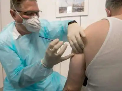 Ein  Rettungsassistent impft  einen Mann gegen Covid-19. Bei der Frage nach mehr Freiheitsrechten f&uuml;r Geimpfte war der Landtag uneins