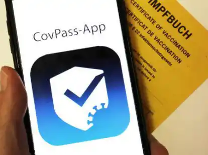 ILLUSTRATION - Das Logo der CovPass-App ist neben einem Impfbuch auf einem Smartphone zu sehen. Der digitale Corona-Impfpass in Deutschland soll an diesem Donnerstag an den Start gehen. (zu dpa: 