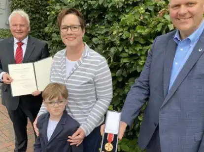 Kerstin Held - im Bild mit Maximilian (7) - erhielt von Thomas Br&uuml;ckmann (links) und Bj&ouml;rn Th&uuml;mler die Urkunde und den Verdienstorden der Bundesrepublik Deutschland.