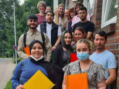 Haben ihren Abschluss geschafft:  Ruba Al Kahido (von unten links), Noora Alyas Aafdw Aafdw, Sayed Ishaq Haidari, Saud Raschied, Ronak Khairi Kret, Baybon Al Rashoo, Lawand Mohammed Wanli, Mohamad Kirwan, mit Vertretern aus dem Bildungswesen. Es fehlt Mohammad Walid Khadrawi.