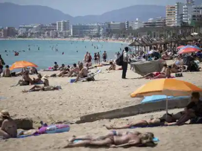 Touristen genie&szlig;en die Sonne an einem Strand auf der spanischen Insel Mallorca.