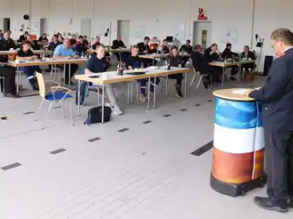 In der Fahrzeughalle des Wildeshausener Feuerwehrhauses: Kreis-Jugendfeuerwehrwart Werner Mietzon (rechts, vorne) begr&uuml;&szlig;t viele Anwesende zum Kreis-Jugendfeuerwehrtag.