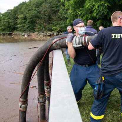 Helfer des Technischen Hilfswerks (THW) lassen Schläuche in die Steinbachtalsperre hinab, um das Wasser abzupumpen. Der Damm der Talsperre droht einstürzen.