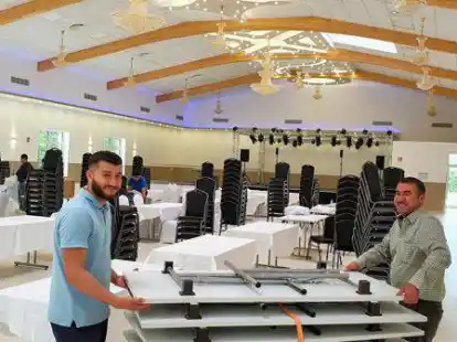 Vorbereitungen f&uuml;r die ersten Veranstaltungen: Sfian (l.) und Jundi Ommer (r.) bauen mit weiteren Familienmitgliedern die Tische in dem neuen Saal auf.