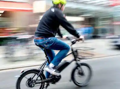 Ein Radfahrer f&auml;hrt mit einem E-Bike auf einer Fahrradstra&szlig;e.