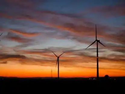 Windkraftanlagen vor einem r&ouml;tlich verf&auml;rbten Abendhimmel (Symbolbild): Um die Energiewende zu erm&ouml;glichen, sollen mehr Windr&auml;der gebaut werden. Doch &uuml;ber die Standorte wird heftig gestritten.