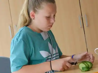 Schnippeln f&uuml;r die Kaninchen: die neunj&auml;hrige Jule schneidet bei ihrem Besuch im Tierheim Salatgurken klein.