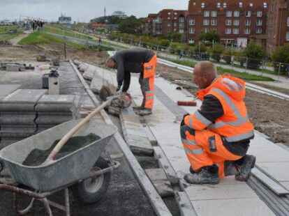 Wilfried Weyerts und Alwin Hanssen (r.) arbeiten mit Hochdruck daran, die letzten Steine am Deich zu verlegen.