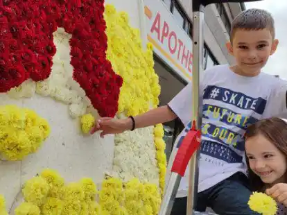 Es stecken die Geschwister Vuk und Miona Stojencevic f&uuml;r den Aufsteller vor dem Gesch&auml;ft der Sonnen-Apotheke im Rahmen des 69. Bl&uuml;tenfestes in Wiesmoor.